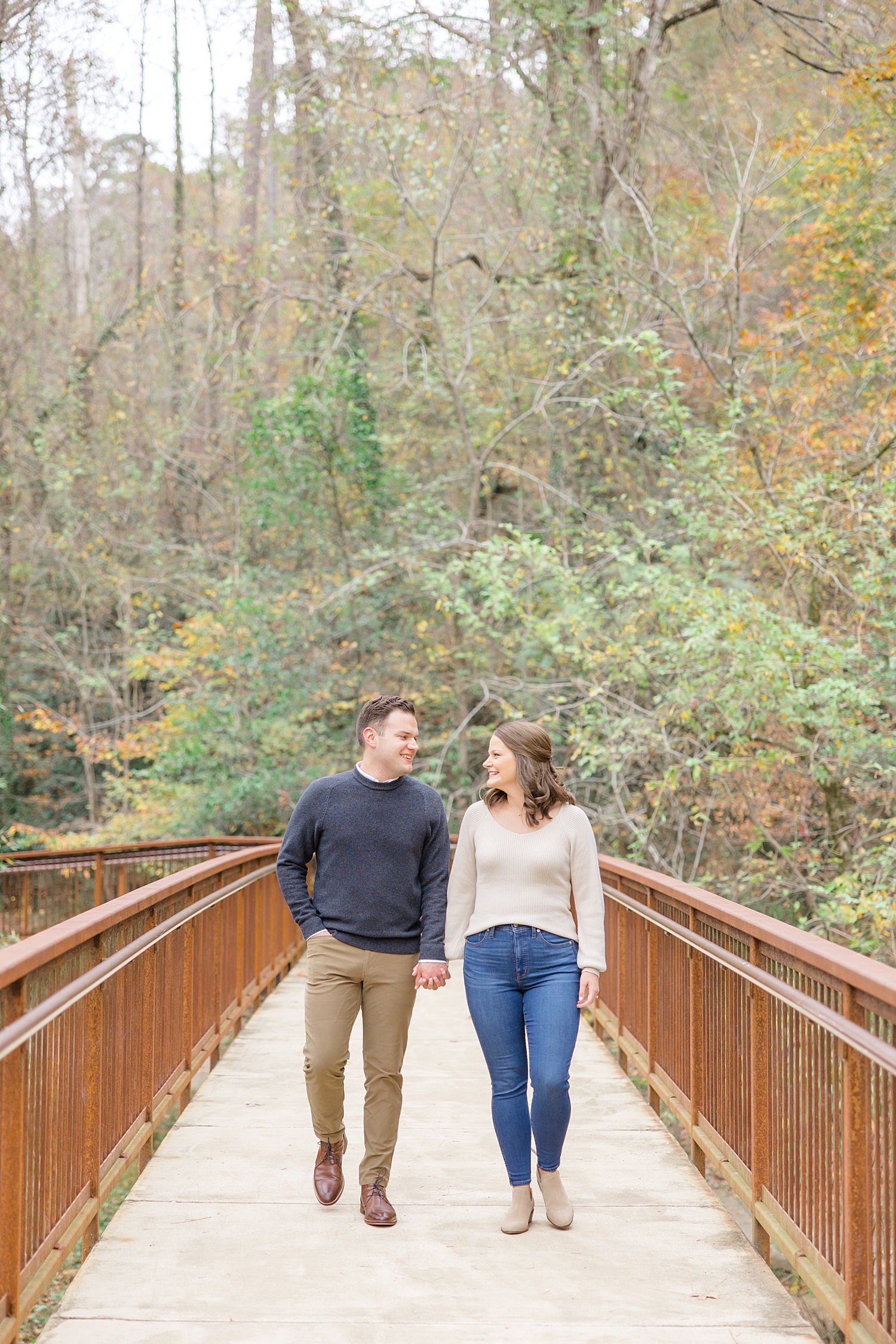newly engaged couple walk across bridge at trail 