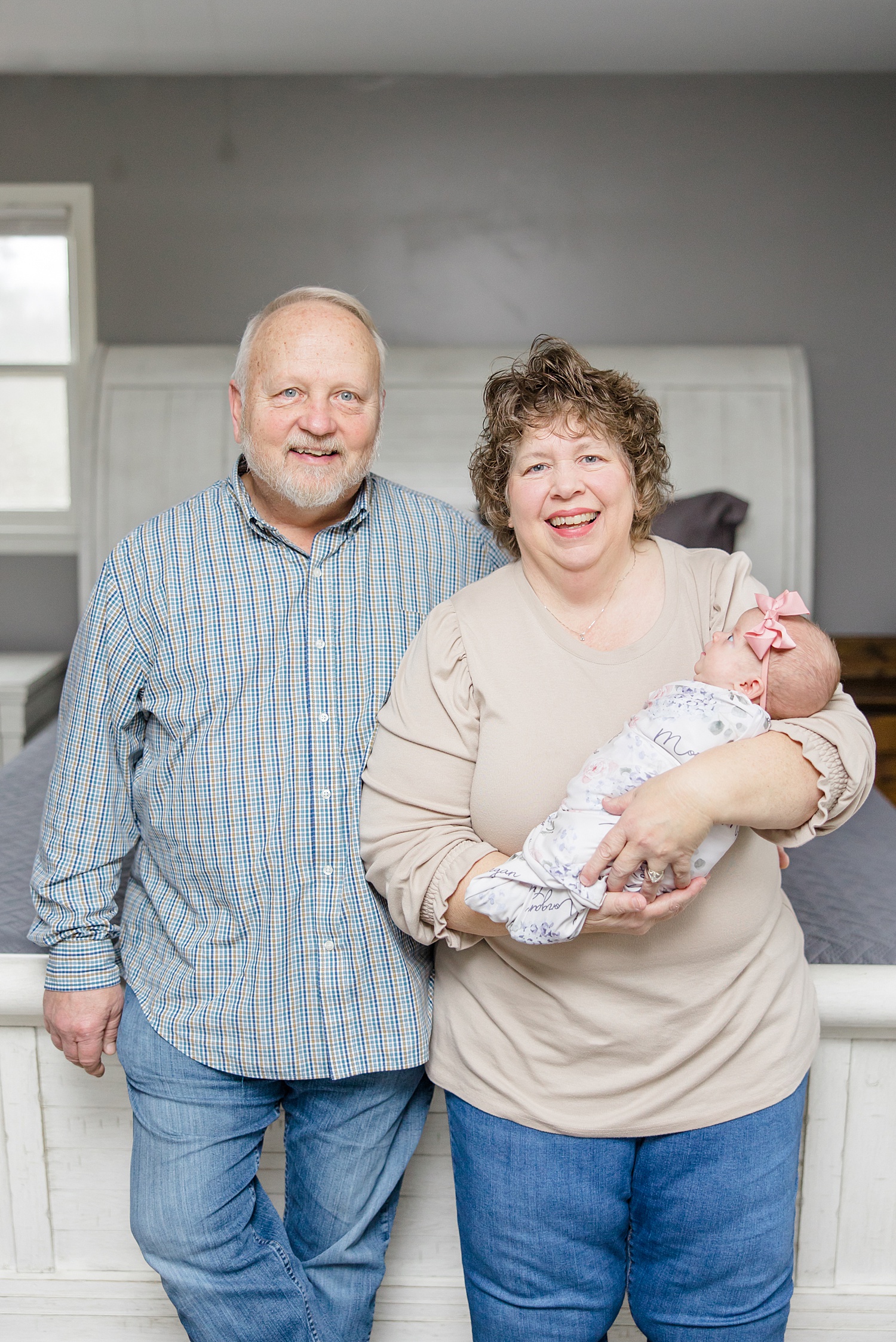 grandparents hold newborn granddaughter