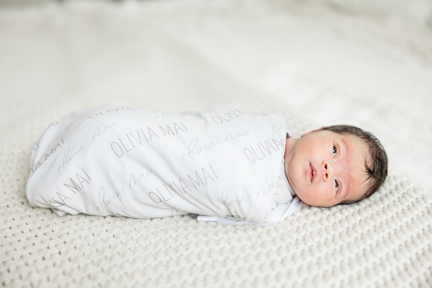 little girl swaddled in personalized white blanket