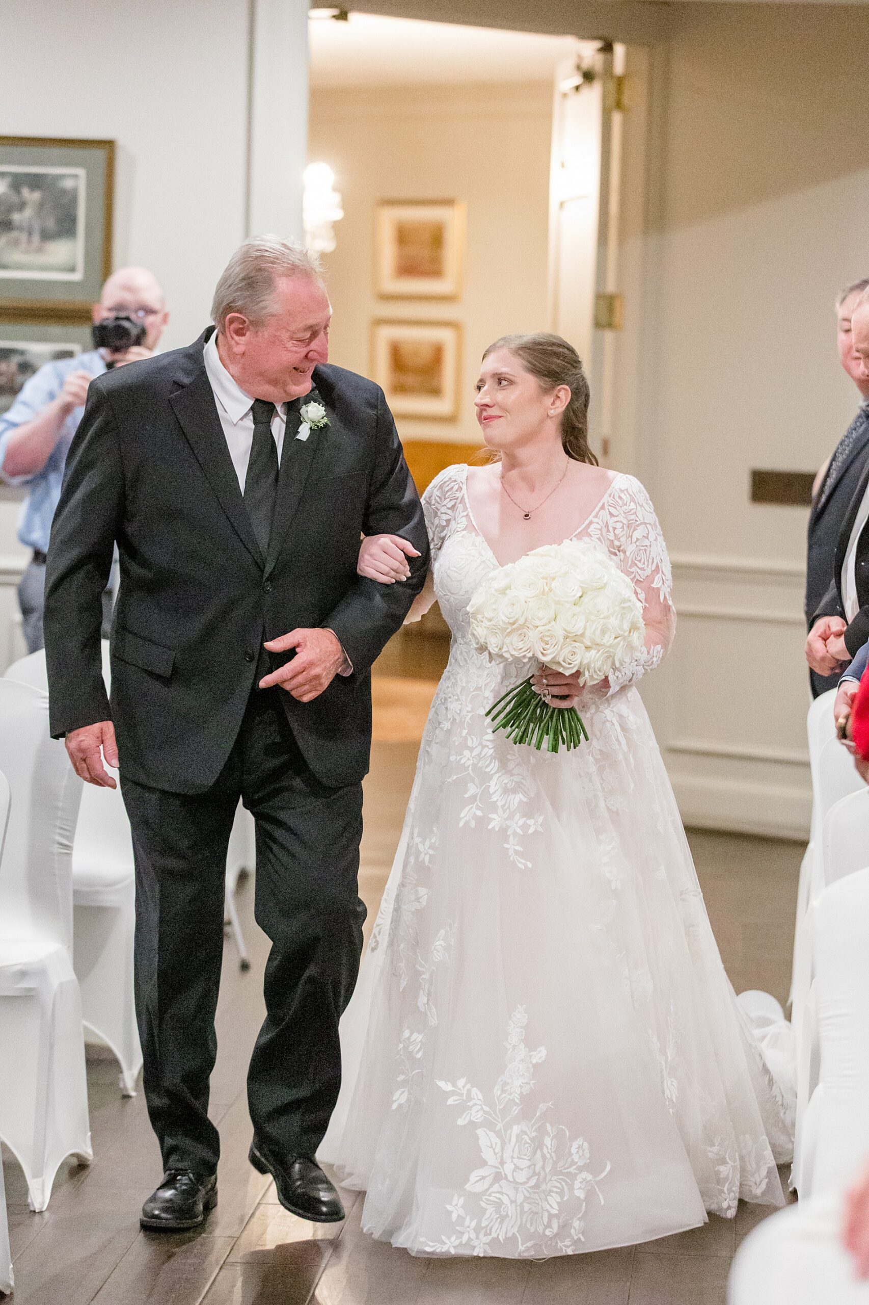 father of the bride and bride share a moment as they walk down the aisle together