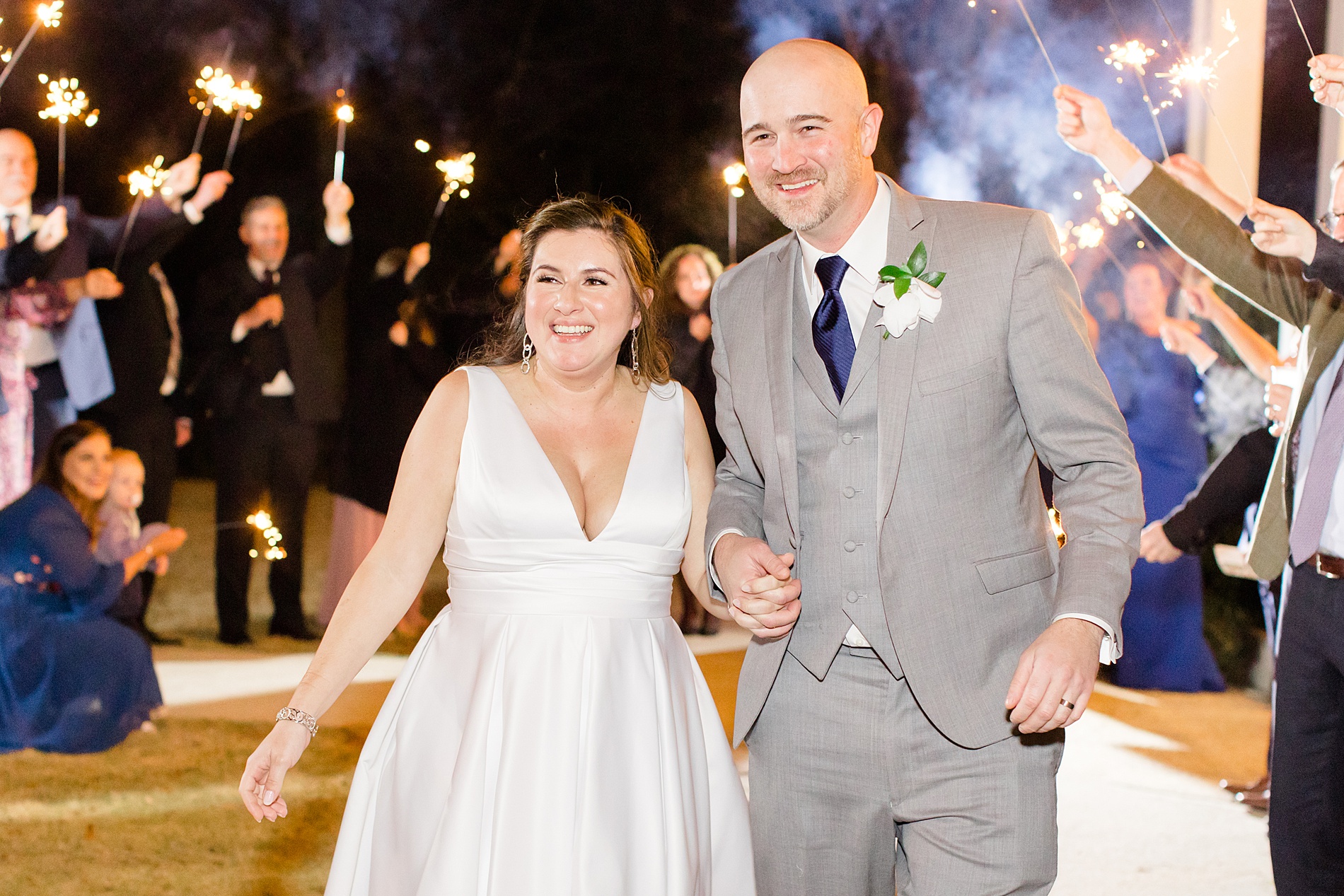 couple exit wedding reception as guests hold sparklers 