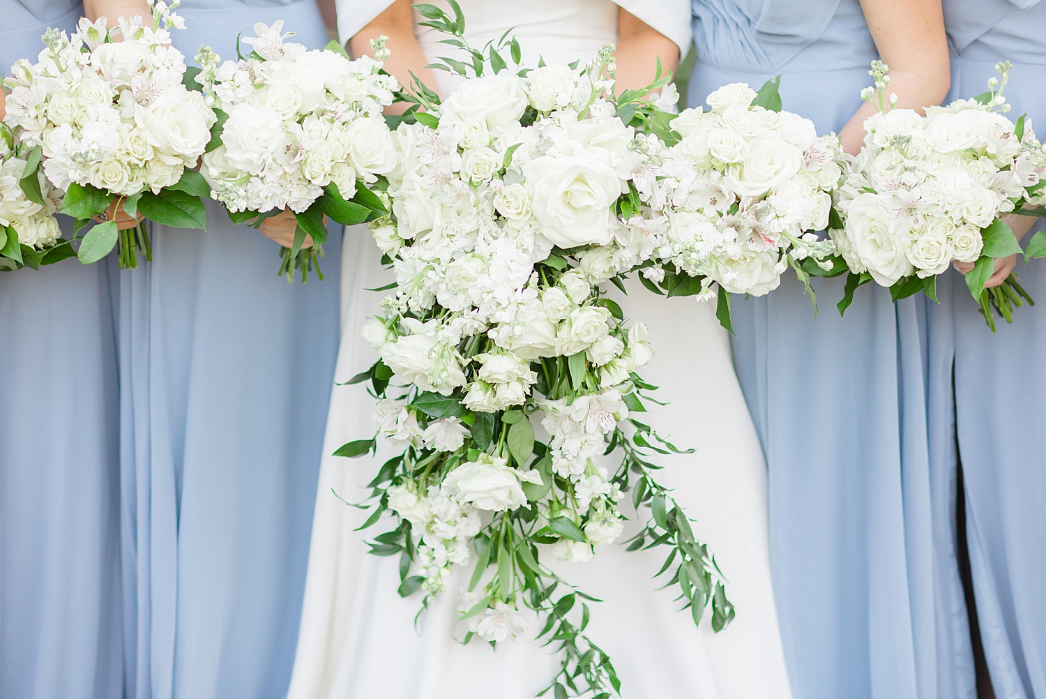bride and bridesmaids hold white wedding flower bouquets