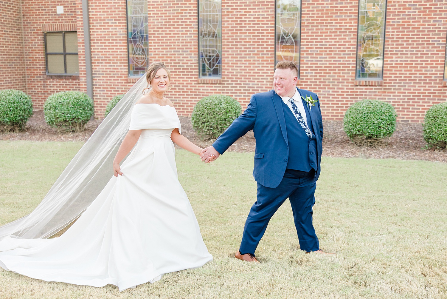 groom leads bride across lawn before Birmingham Wedding at B&A Warehouse 