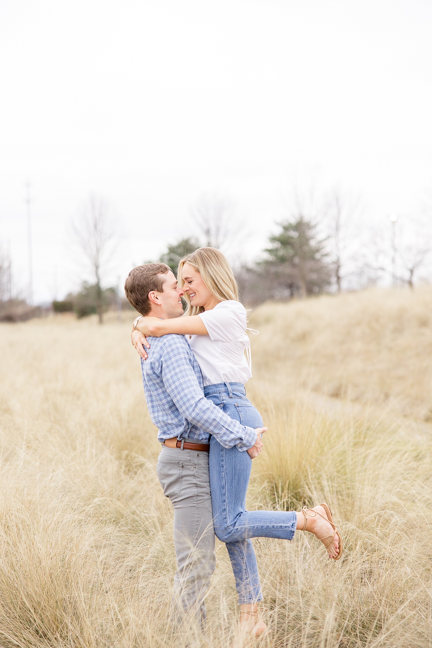 man lifts his fiance up during engagement session