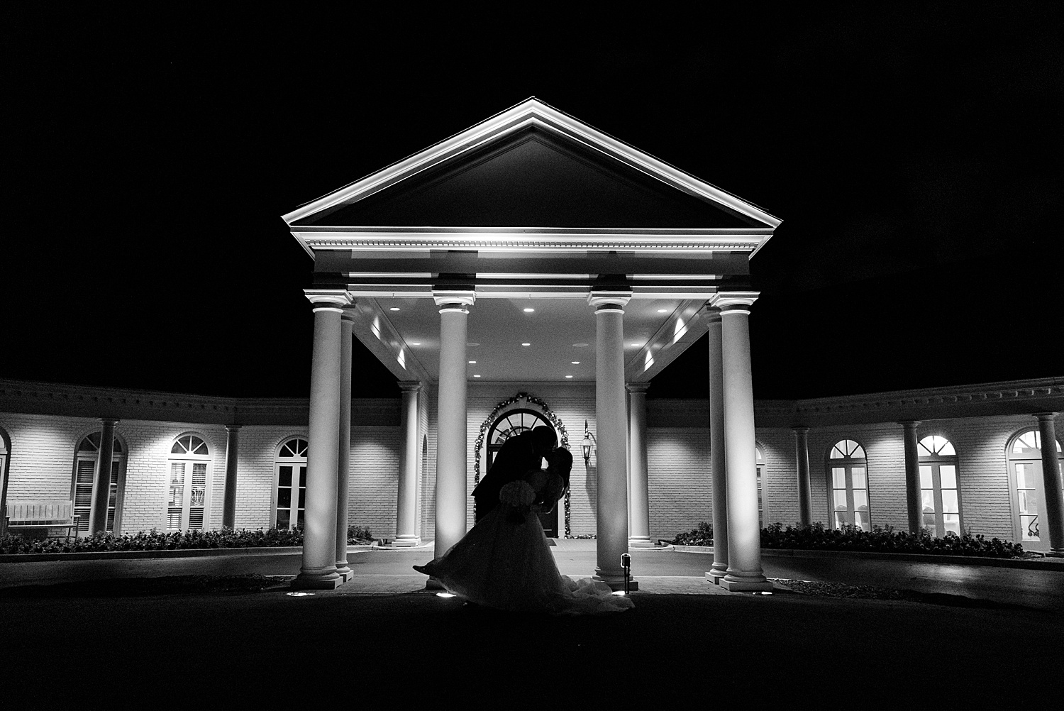 newlyweds kiss outside of Vestavia Country Club at night