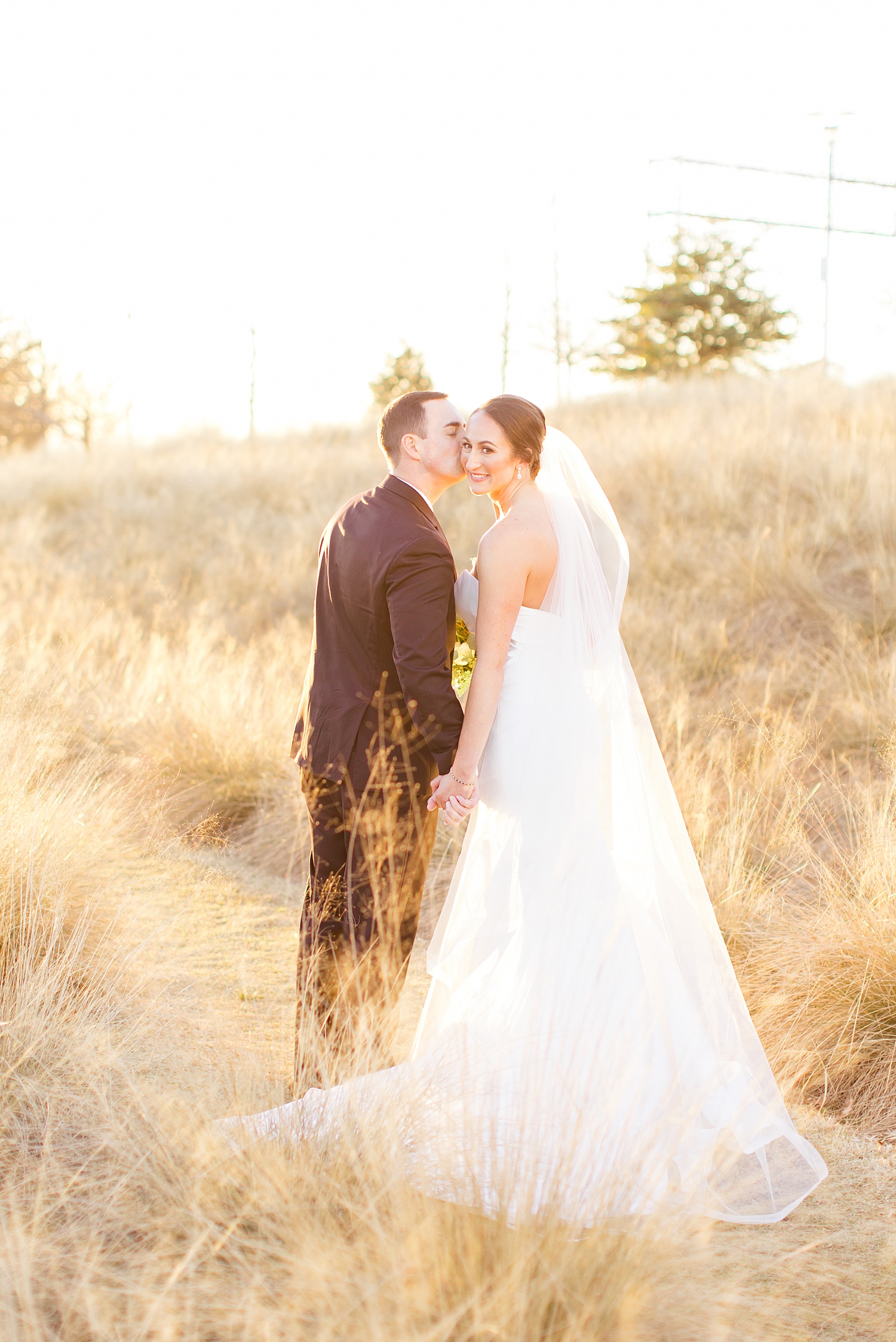groom kisses bride during sunset wedding portraits