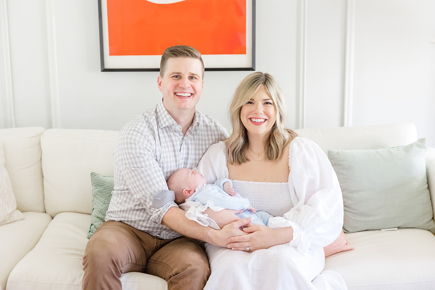 parents hold newborn boy on couch