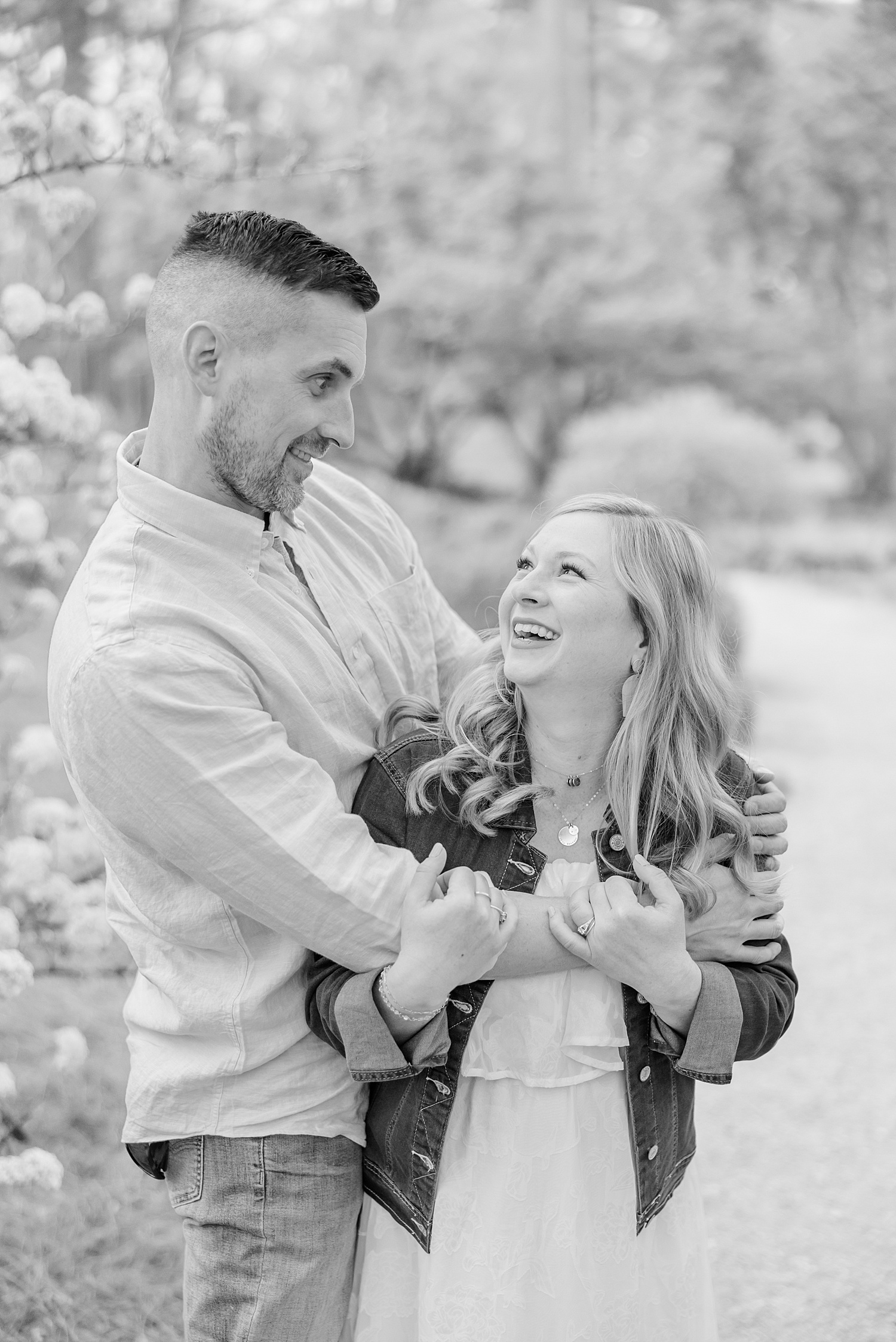 couple laugh together during their maternity portraits 