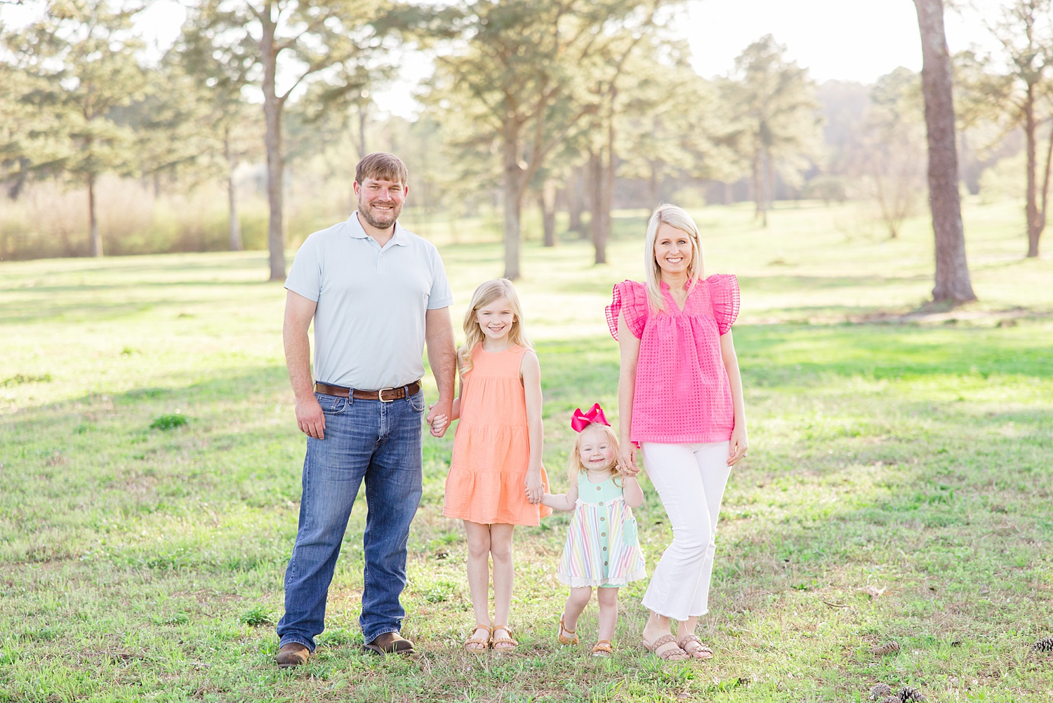 family of four hold hands in field during Spring Mini Sessions 